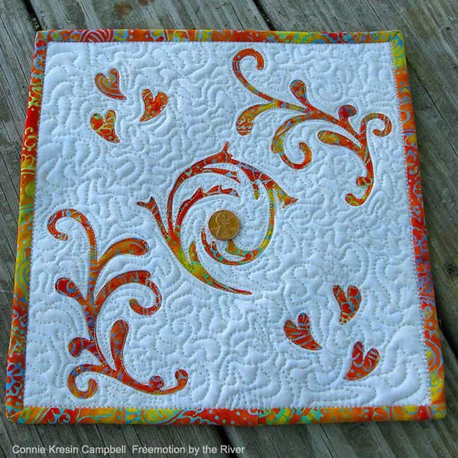 Mini batik quilt with a penny on it