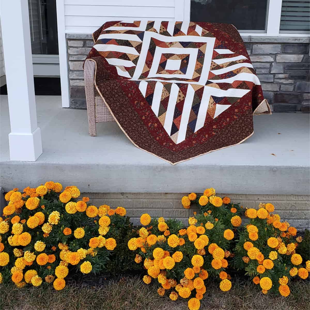 Sienna Arrows quilt on porch with marigolds
