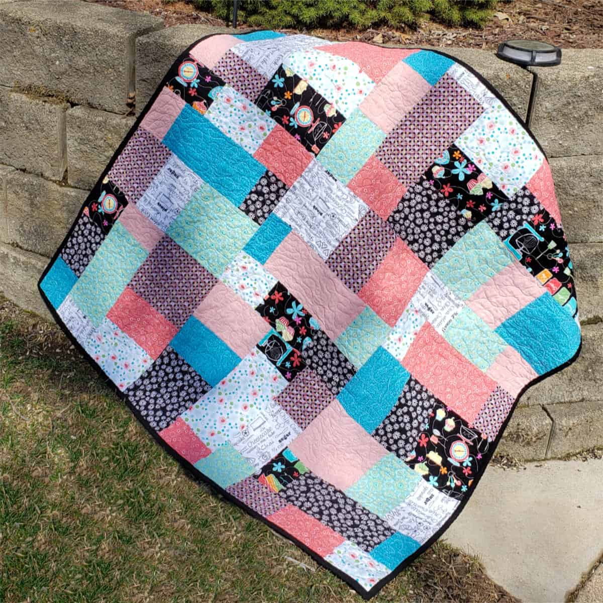 Stacks baby quilt outside on wall