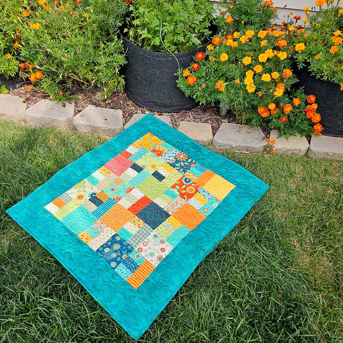 Scrappy teal quilt on ground